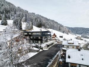 a town with snow covered buildings and a mountain at Timeless Dolomites Apartments in Dobbiaco