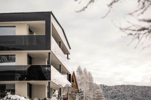 a building with snow on the ground and trees at Timeless Dolomites Apartments in Dobbiaco