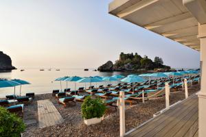 ein paar Stühle und Sonnenschirme am Strand in der Unterkunft La Plage Resort in Taormina