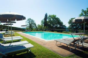 a swimming pool with chairs and umbrellas next to at Castellaccia contemporary country house in San Gimignano