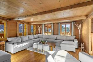 ein Wohnzimmer mit einem großen Sofa und einem Tisch in der Unterkunft Mountain Chalet - Panoramic Terraces - Near Gstaad in Devant