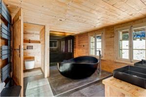 a large black bath tub in a wooden bathroom at Mountain Chalet - Panoramic Terraces - Near Gstaad in Devant