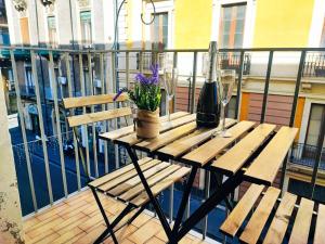une table en bois avec des fleurs et des verres sur un balcon dans l'établissement DUHOME apartment in the heart of Catania, à Catane