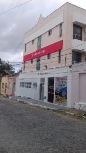 a white building with a red sign on it at Várzea HOTEL in Sobral