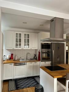 una cocina con armarios blancos y electrodomésticos de acero inoxidable en Luxurious House for Rent, en Pristina