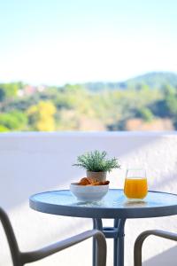 a table with a glass of orange juice and a plant at Telis Hotel in Agia Paraskevi