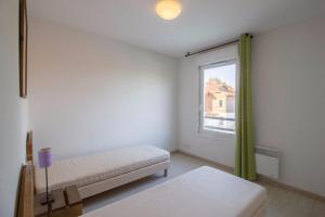 um quarto branco com uma cama e uma janela em Les Terrasses du Lac J43 em Aureilhan