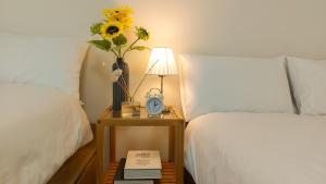 a bed with a table with a clock and a vase with flowers at Adi Stay in Seoul