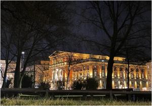 a large building is lit up at night at Operngasse-Karlsplatz in Vienna