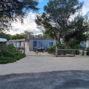 ein Haus mit einem Hund, der hinter einem Zaun steht in der Unterkunft Kookaburra Lodge in Lock Sport