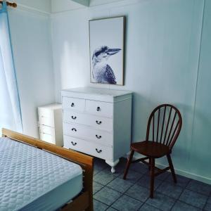 ein Schlafzimmer mit einer Kommode, einem Stuhl und einem Bild in der Unterkunft Kookaburra Lodge in Lock Sport