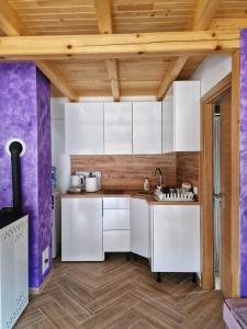 a kitchen with white cabinets and wooden ceilings at Stara pruga Jaz 2 in Višegrad