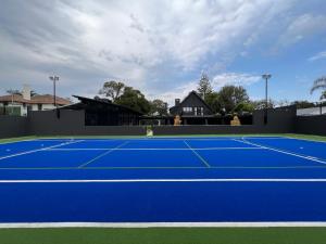 a blue tennis court with a house in the background at The Clubhouse in Walmer