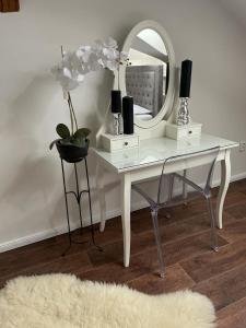 a white desk with a mirror and a vase with flowers at Apartmán in Kadaň