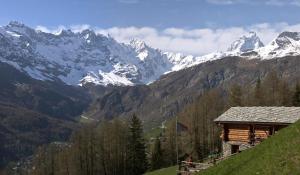 a snow covered mountain range with a building on a hill at B&B Lepetitnid in Valtournenche