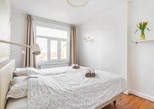 a white bedroom with a bed and a window at Vitaflow logies in Koksijde