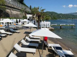 uma praia com cadeiras de praia brancas e guarda-sóis em casa/studio Ricard Centro storico Arona em Arona