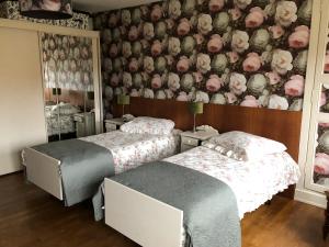 - 2 lits dans une chambre avec papier peint floral dans l'établissement Le Voyageur, à Saint-Bonnet-Tronçais