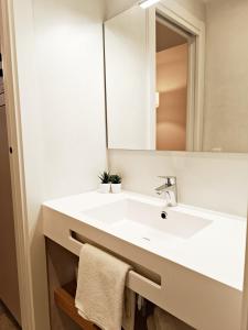 y baño con lavabo blanco y espejo. en ARIQUS Fira Apartments, en Hospitalet de Llobregat