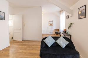 ein Wohnzimmer mit einem schwarzen Sofa und 2 Kissen in der Unterkunft Coquelin - Joli appartement rénové in Rennes