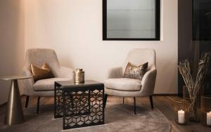 two chairs and a table in a living room at Timeless Dolomites Apartments in Dobbiaco
