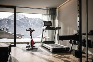 a room with a gym with a treadmill and a window at Timeless Dolomites Apartments in Dobbiaco