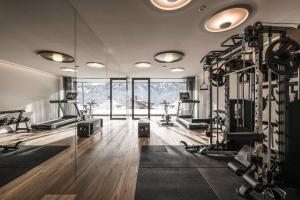 a gym with treadmills and machines in a room at Timeless Dolomites Apartments in Dobbiaco