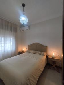 1 dormitorio con 1 cama grande, 2 mesas y luz en Villa Naranjo, en Sevilla