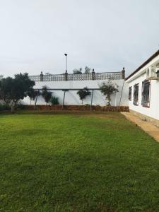 un edificio blanco con un césped verde delante de él en Villa Romero, en Mairena del Alcor