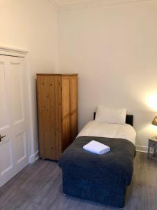 a small bedroom with a bed and a wooden cabinet at Spare Room Stay in Edinburgh