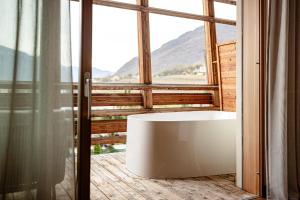 ein Bad mit einer Badewanne vor einem Fenster in der Unterkunft Lake Spa Hotel SEELEITEN in Kaltern