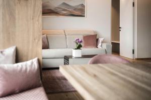 a living room with a couch and a table with flowers at Timeless Dolomites Apartments in Dobbiaco