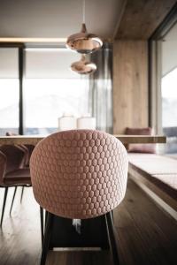 a brown chair sitting in front of a table at Timeless Dolomites Apartments in Dobbiaco