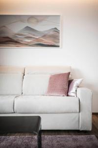 a white couch in a living room with a painting at Timeless Dolomites Apartments in Dobbiaco