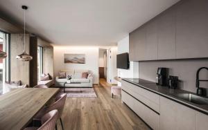a kitchen and living room with a table and a couch at Timeless Dolomites Apartments in Dobbiaco