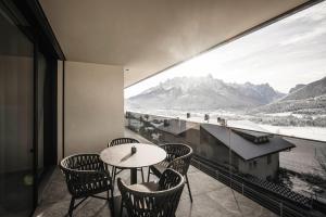 a balcony with a table and chairs and a view of mountains at Timeless Dolomites Apartments in Dobbiaco