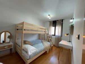1 dormitorio con litera, mesita de noche y mesa en Apartamento La Añaza, en Villanúa