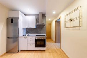 una cocina con nevera de acero inoxidable y armarios blancos en Exclusive & cozy apartment in the center of Soria, en Soria