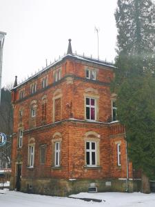 a large red brick building in the snow at Kot Pocztowy in Długopole-Zdrój