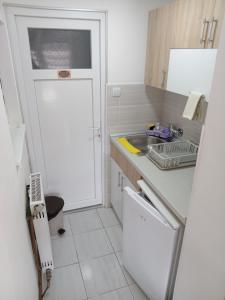 a small white kitchen with a sink and a door at APARTMAN “POD KRALJEVICOM” in Zaječar