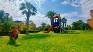 a playground in a park with palm trees at Atlas Views By Golf Resort in Marrakesh