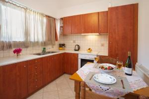 アギア・エフィミアにあるFaos Luxury Apartmentsのキッチン(木製キャビネット、ワイングラス付きのテーブル付)