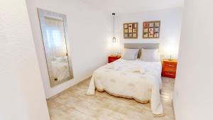 una camera da letto bianca con un letto e uno specchio di Apartamento Net by Family Homes a Denia