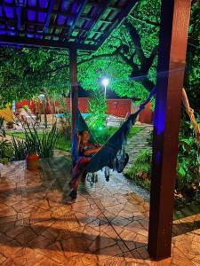 - une personne dormant dans un hamac sous une pergola dans l'établissement Pousada Jardim de Minas, à La Serra do Cipo