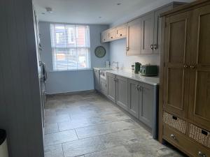 ベバリーにあるImmaculate central 4-Bed townhouse in Beverleyのタイルフロアのキッチン(白いキャビネット付)