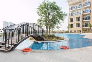 a bridge over a swimming pool with orange frisbees at Modern Studio In Resortz Residence - Arjan in Dubai