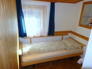 Bett in einem Zimmer mit einem Fenster mit blauen Vorhängen in der Unterkunft Runatsch 133 A in Zernez