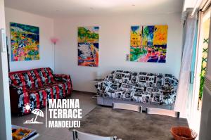 a living room with a couch and paintings on the walls at Marina Terrace in Mandelieu-la-Napoule