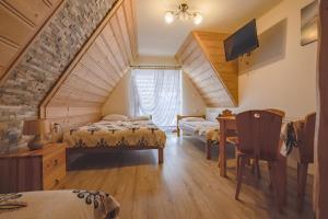 a attic bedroom with two beds and a desk at U Marii & Mariana in Leśnica