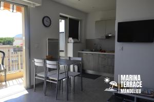 een keuken met een tafel en stoelen en een televisie bij Marina Terrace in Mandelieu-la-Napoule